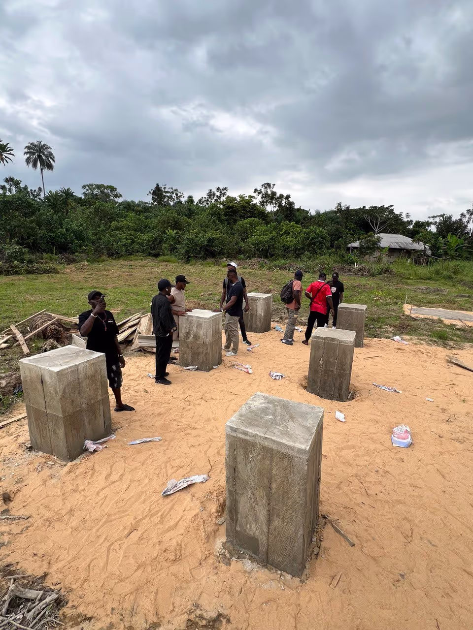 Six cement pillars where our container will be place on. There are people around the pillars discussing things.